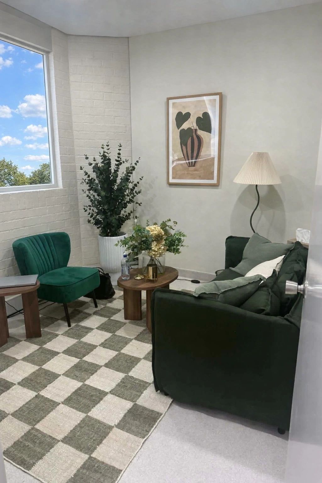 Warm therapy room with cream armchairs, framed art and indoor plants